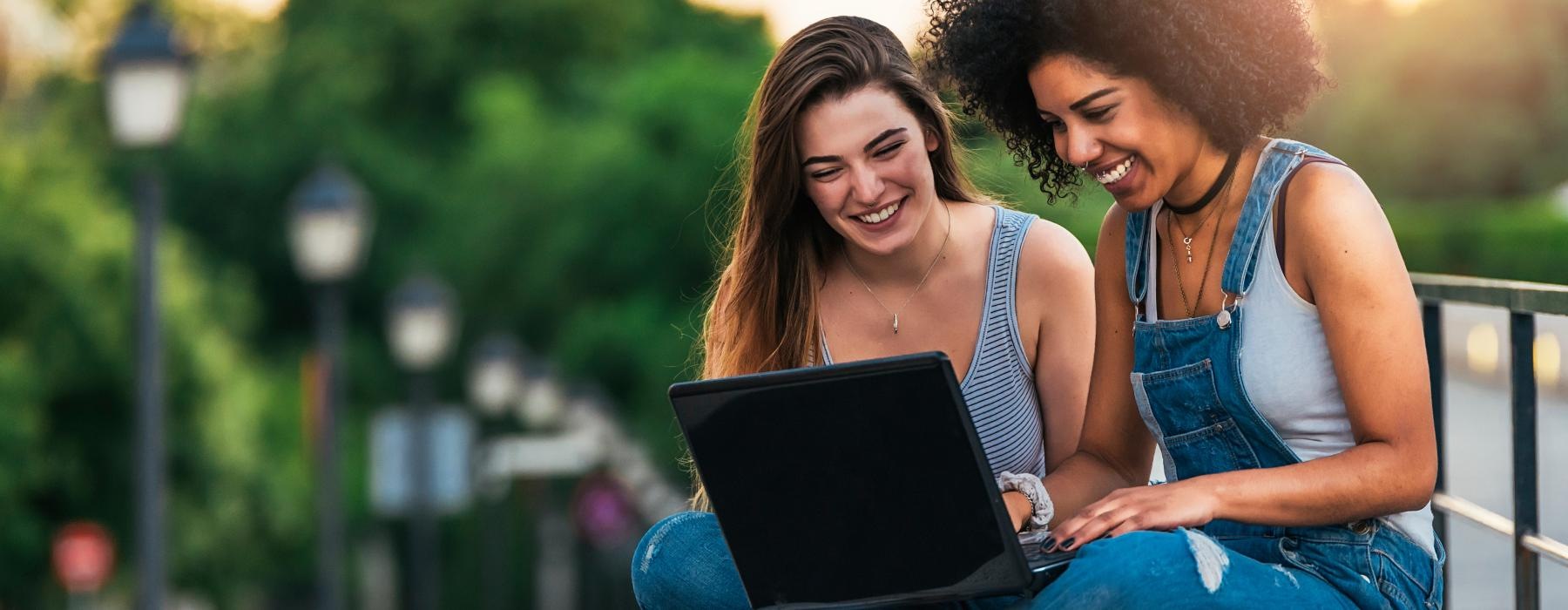 a couple of women looking at a laptop